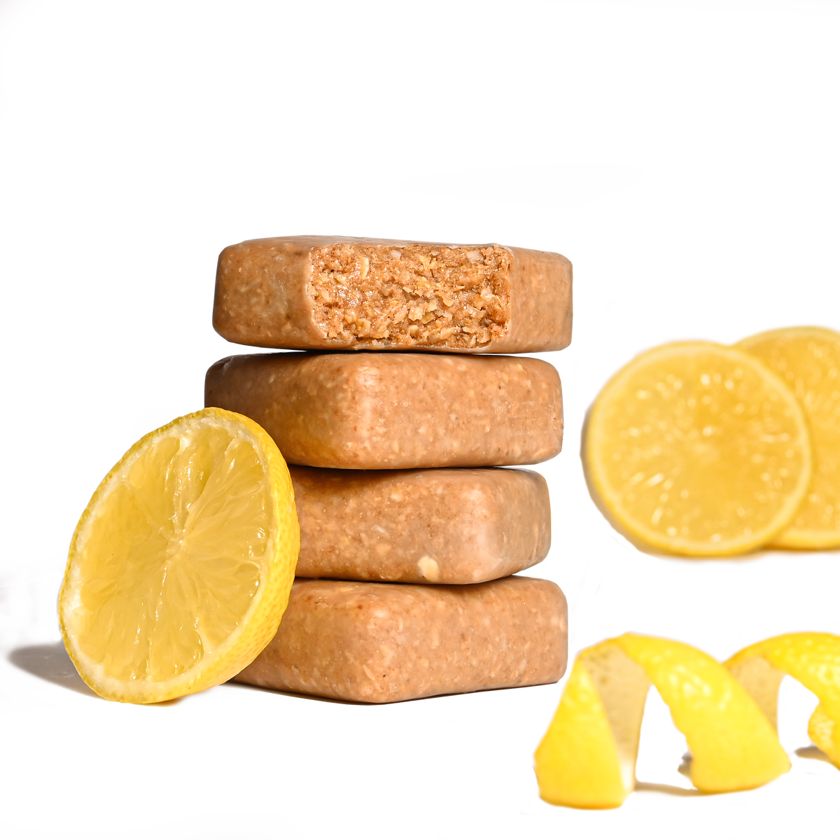 Stack of Performance² Dual-Carb & Electrolyte Energy Bars with lemon slices and a squeezed lemon on a white background.