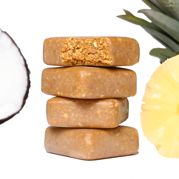 Stack of Performance² Dual-Carb & Electrolyte Energy Bars with pineapple slices on a white background.